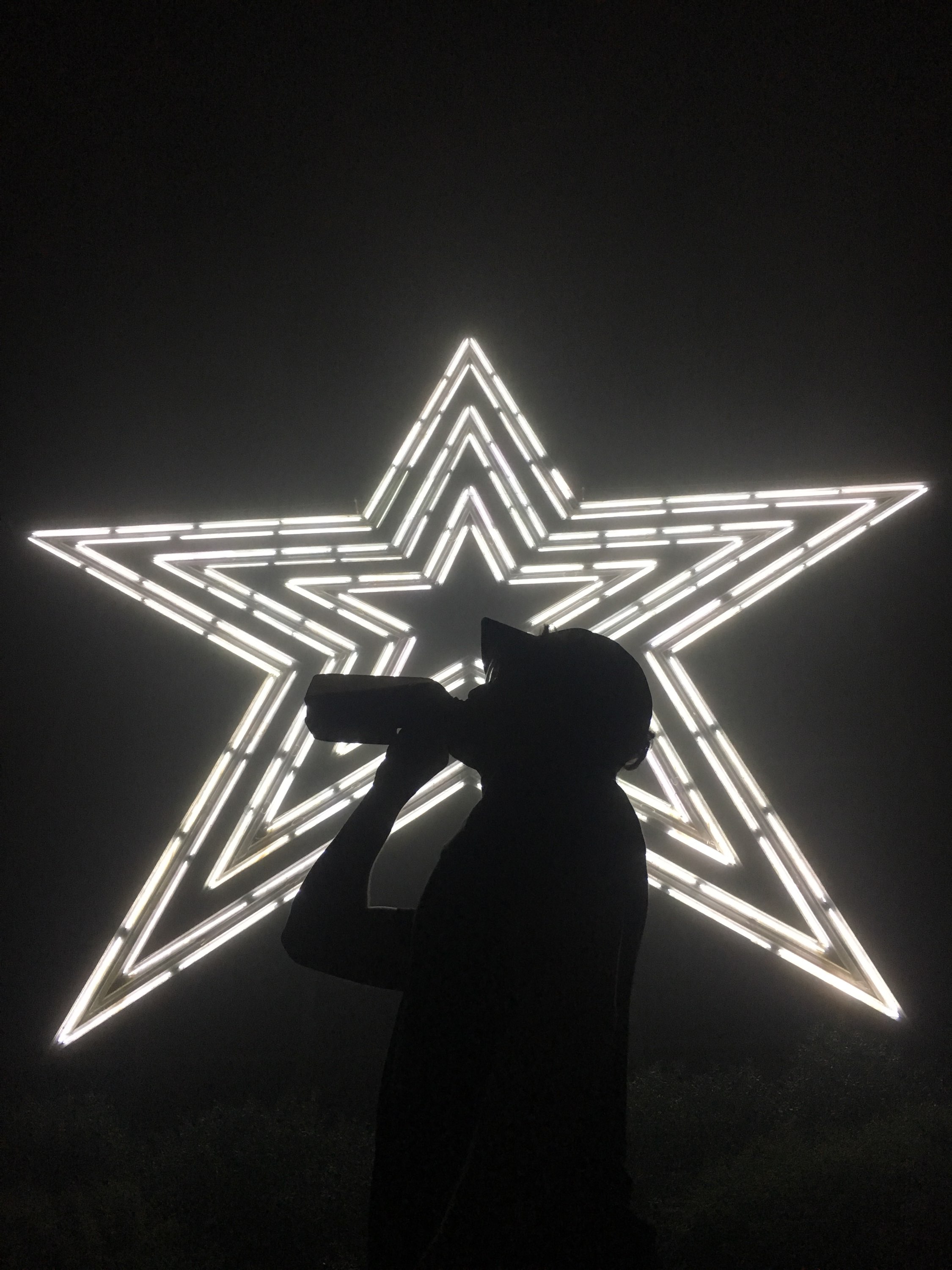 Francesco standing in front of a giant neon star at night